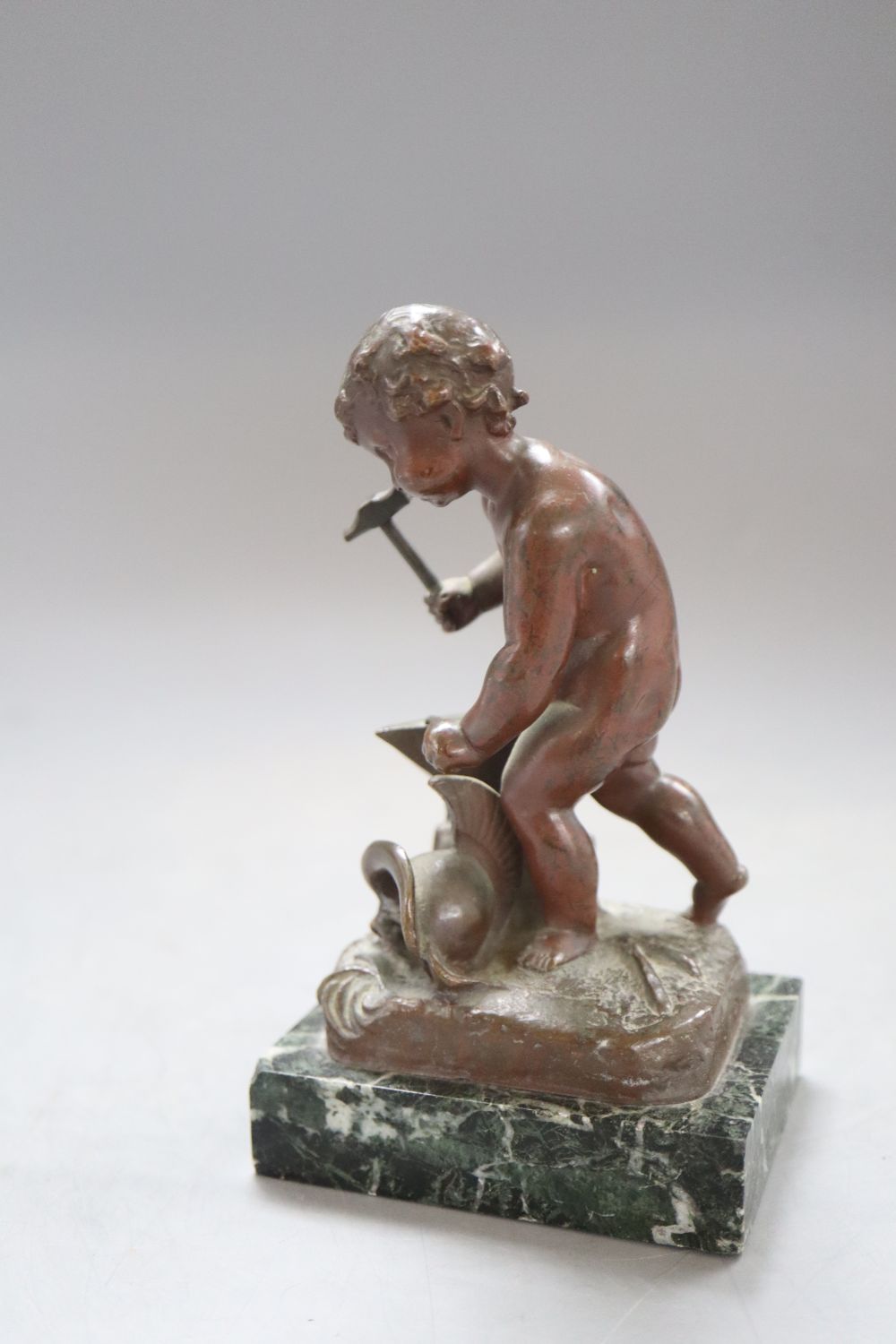 A bronze putto blacksmith, signed H. Capy, on marble base, height 15cm